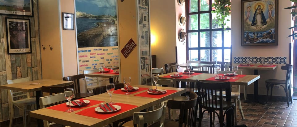 Sala de Al Son de Cuba con varias mesas preparadas con mantel rojo
