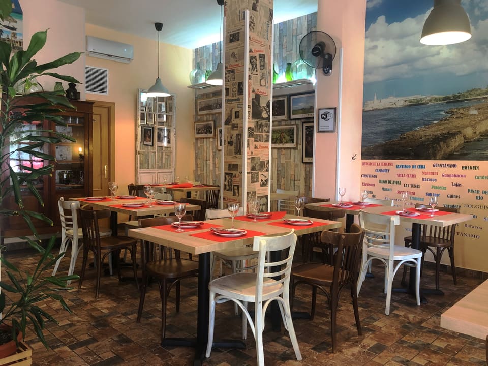 Dining room at Al Son de Cuba: red-set tables, a mural of the Cuban coast and the names of Cuban cities on the wall